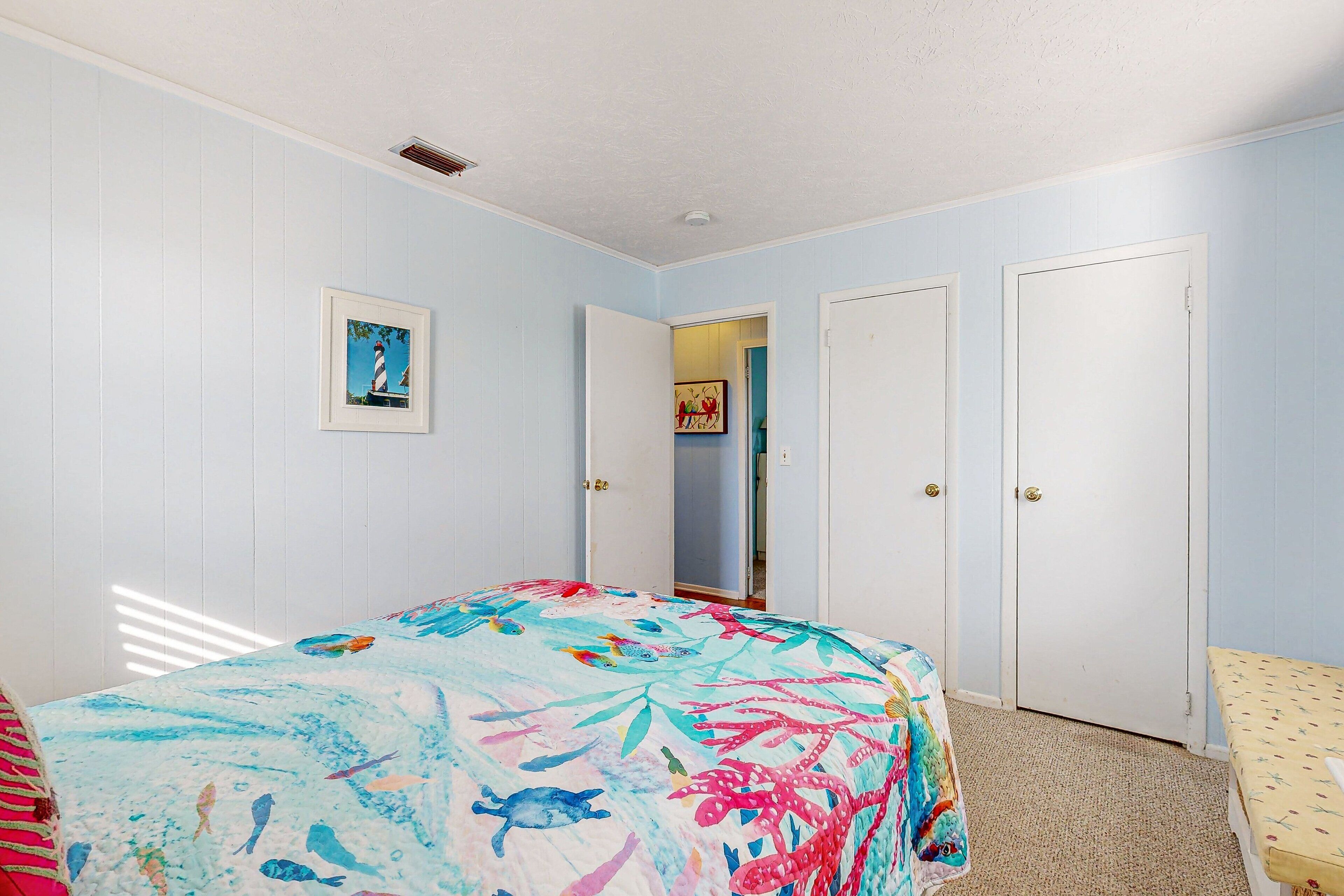 A bedroom with a bed, a door, and a small table.
