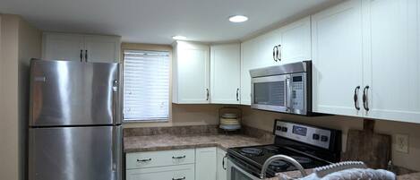 A kitchen with white cabinets, stainless steel appliances, a granite countertop, and a fish-shaped soap dish.
