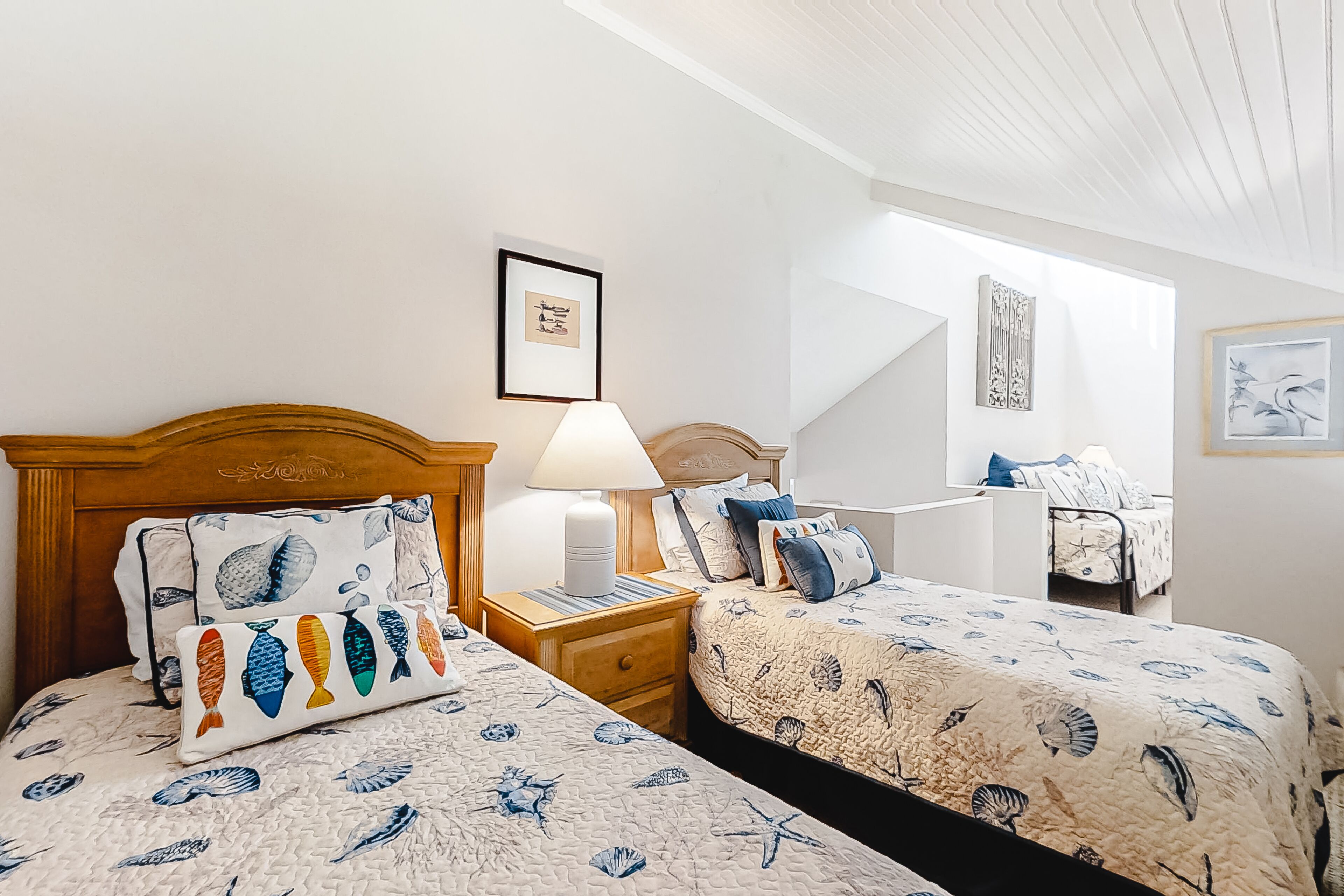 A bedroom with two beds, a nightstand, a lamp, and a framed picture on the wall.