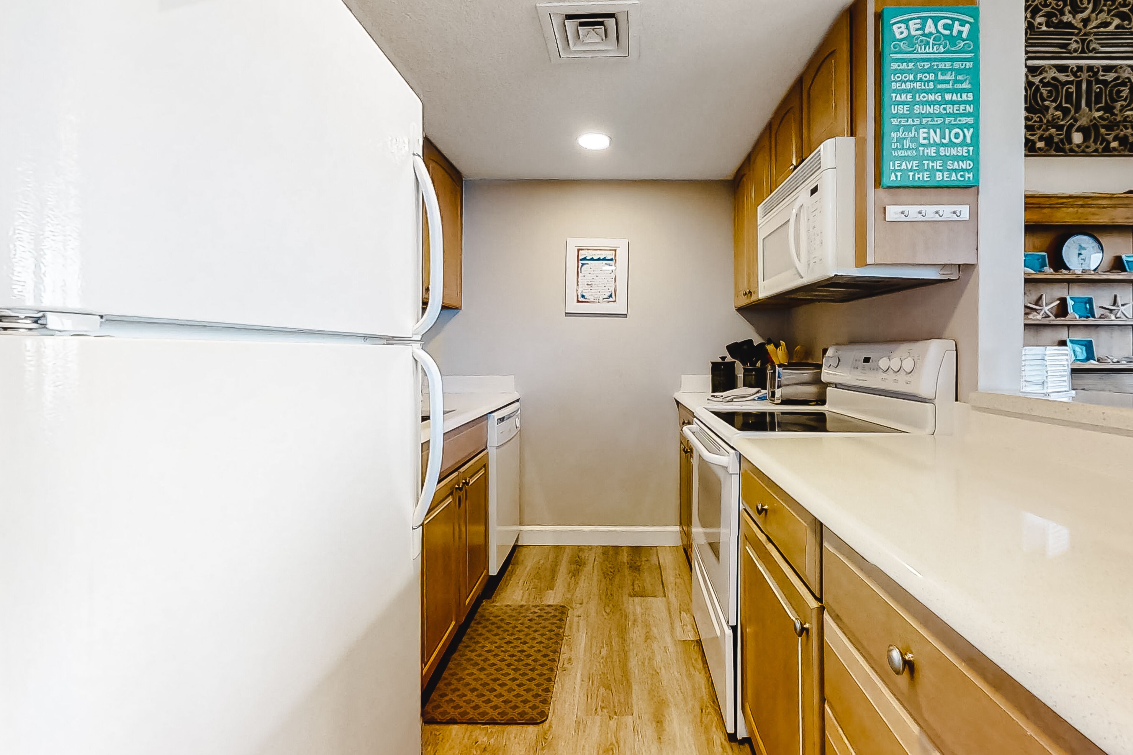 A compact kitchen with white appliances, wooden cabinets, and a small countertop.