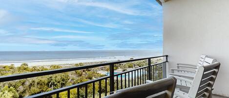 A balcony with a view of the beach and ocean.