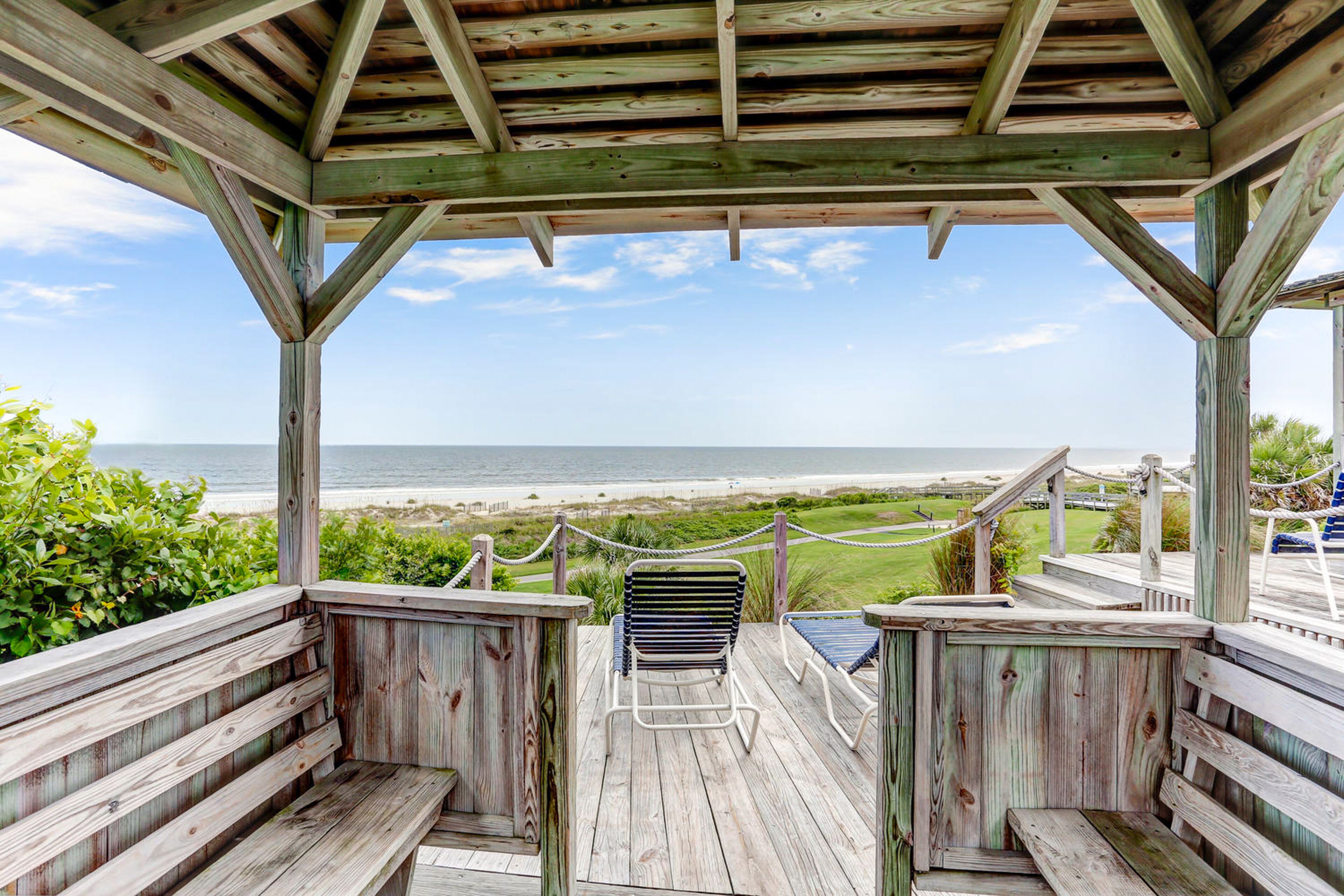 Eine Holzterrasse mit Bänken und Blick auf den Strand.
