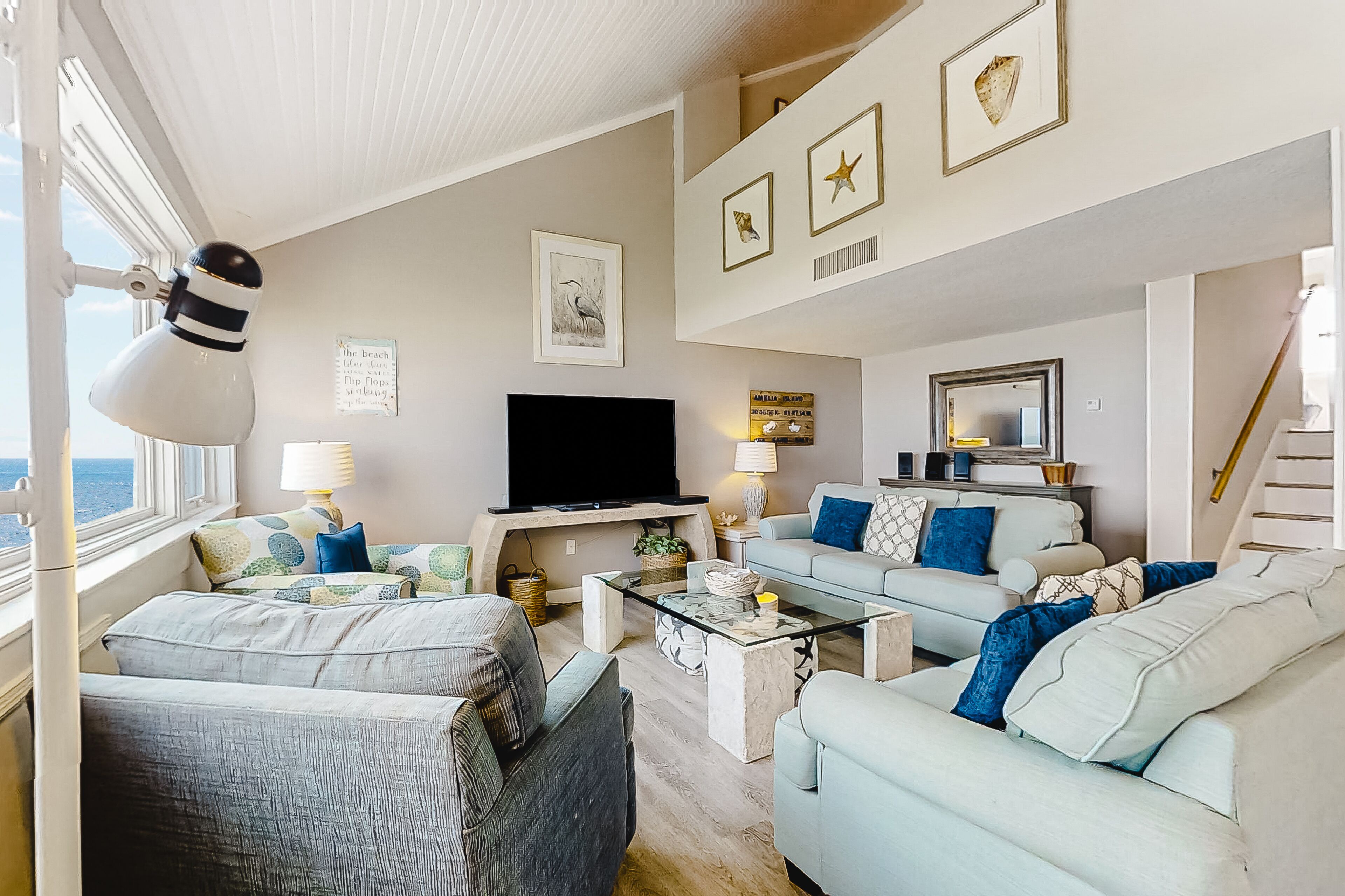 A modern living room with a flat-screen TV, comfortable seating, and artwork on the walls.