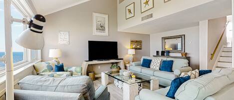 A modern living room with a flat-screen TV, comfortable seating, and artwork on the walls.
