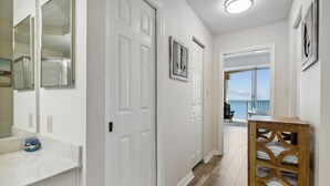 A hallway with white doors, a wooden bench, and a view of the balcony. - Oceanfront Condo,beach Access, Heated Pool, Tennis Courts (Palm Coast)