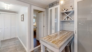 Une cuisine avec des meubles blancs, un plan de travail en bois et un luminaire suspendu.