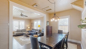 Un salon spacieux comprenant un coin repas, un ventilateur de plafond et un lustre.