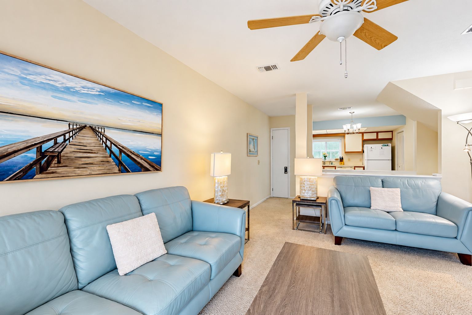 A living room with a blue sofa, a coffee table, a lamp, and a ceiling fan.