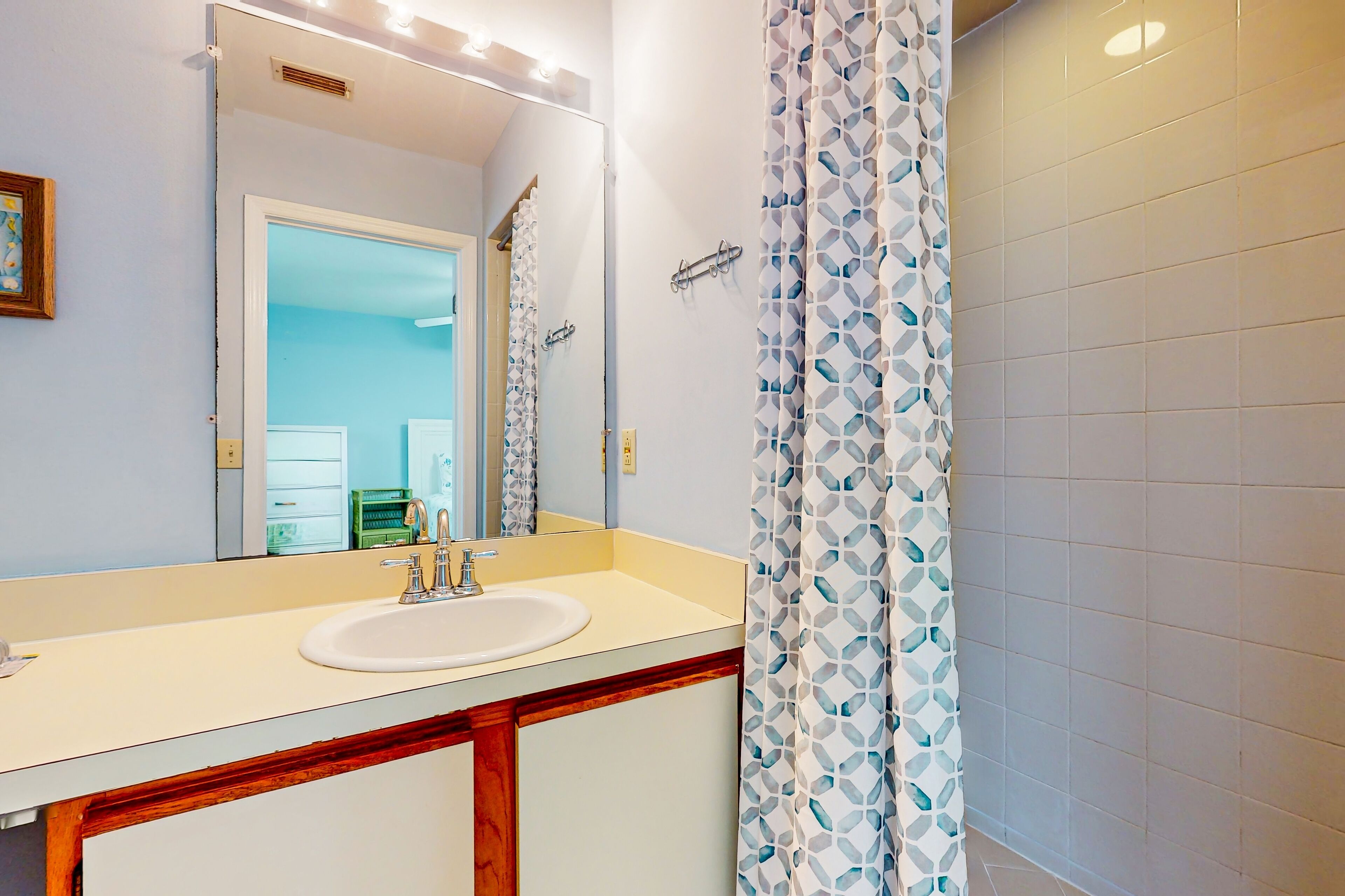 A bathroom with a white sink, mirror, and patterned shower curtain.