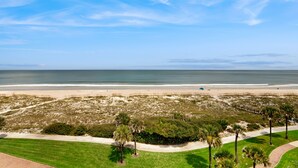 A beach with a pathway, palm trees, and a boardwalk. - Ocean-view Penthouse With Pool, Balcony & Central AC - Snowbird-friendly (Fernandina Beach)