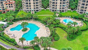 A high-rise hotel with multiple balconies, a central swimming pool, and lush landscaping. - Ocean-view Penthouse With Pool, Balcony & Central AC - Snowbird-friendly (Fernandina Beach)