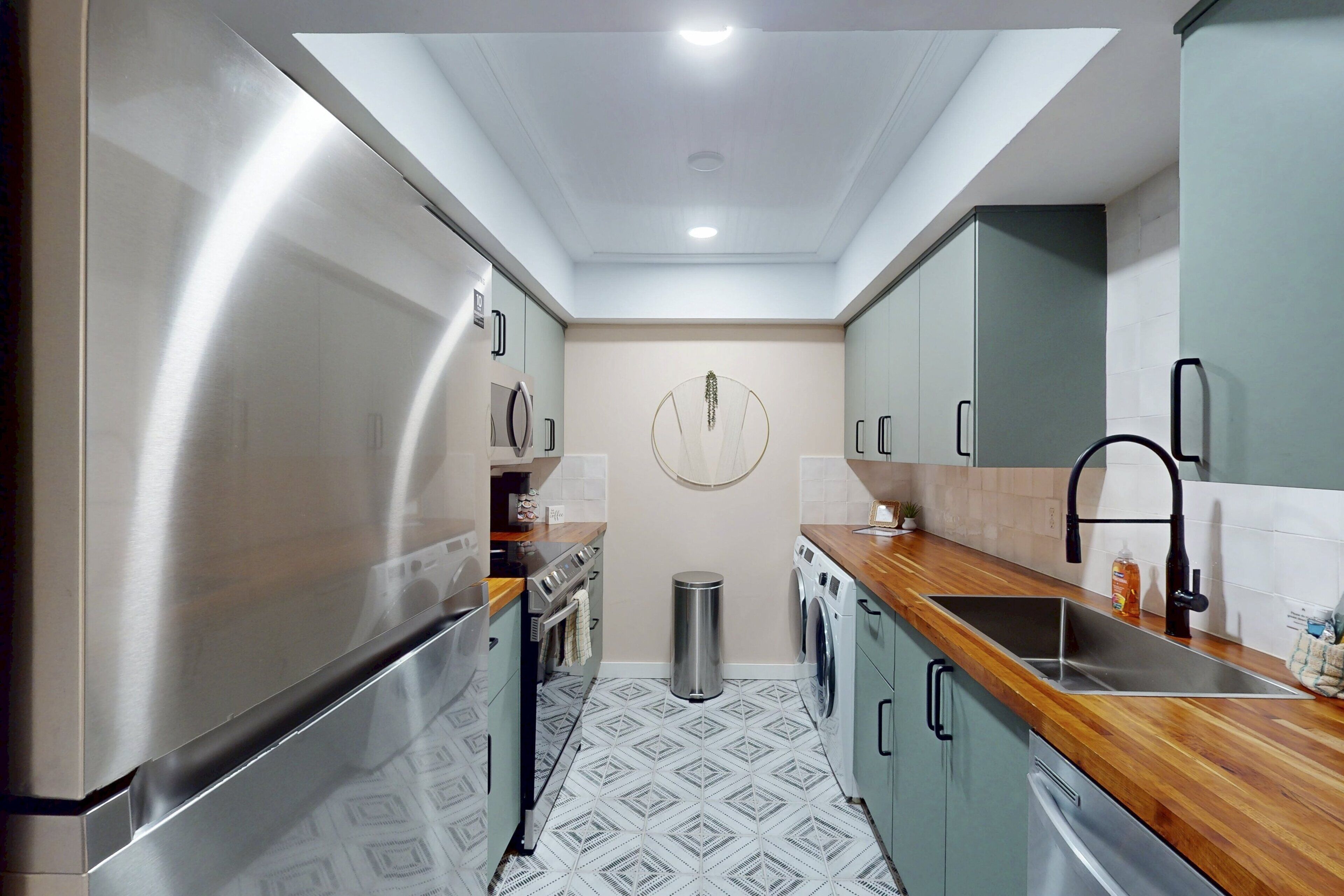 A compact kitchen with stainless steel appliances, a wooden countertop, and a tiled floor.
