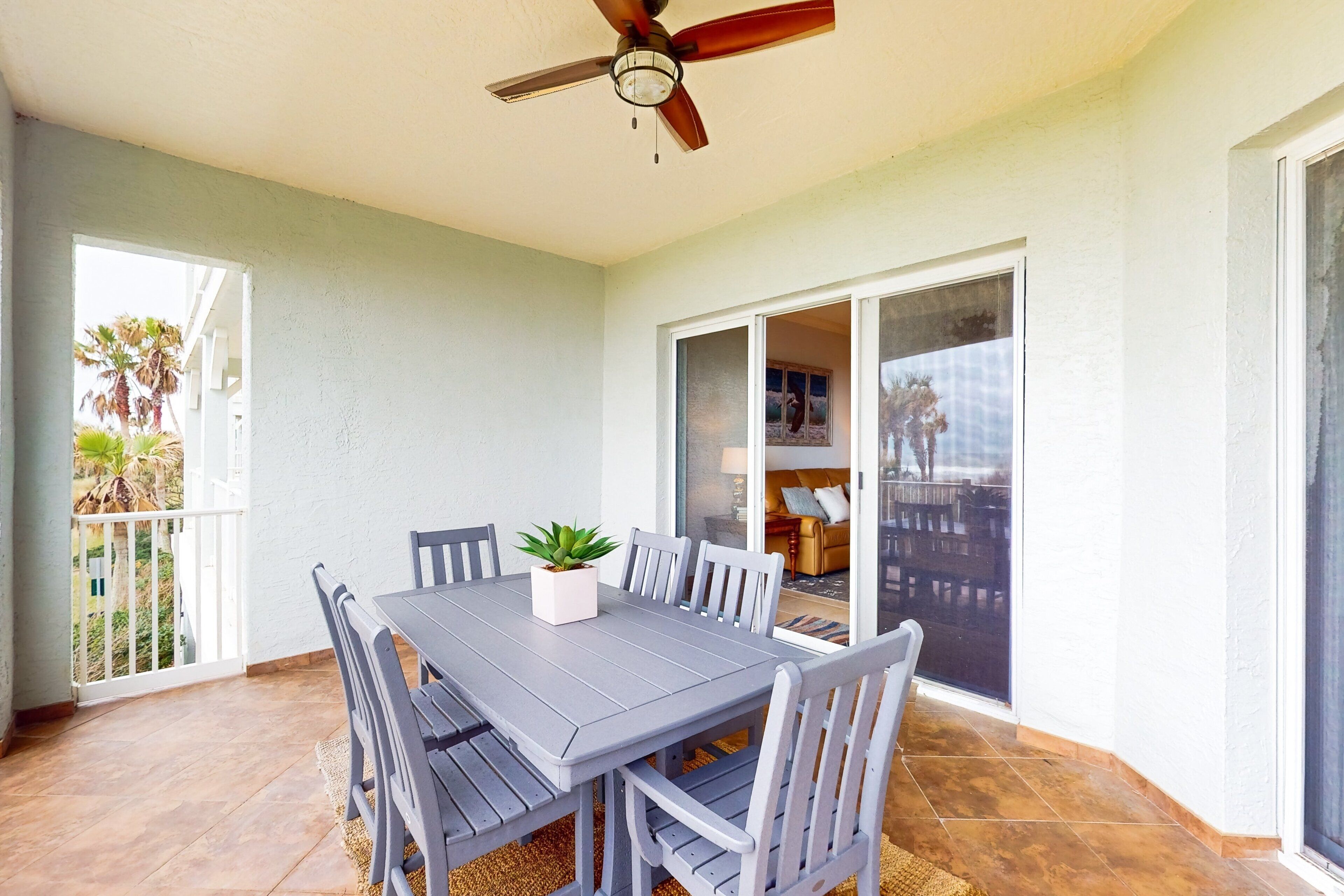 A dining area with a table and chairs, a ceiling fan, and a view of the outdoors.
