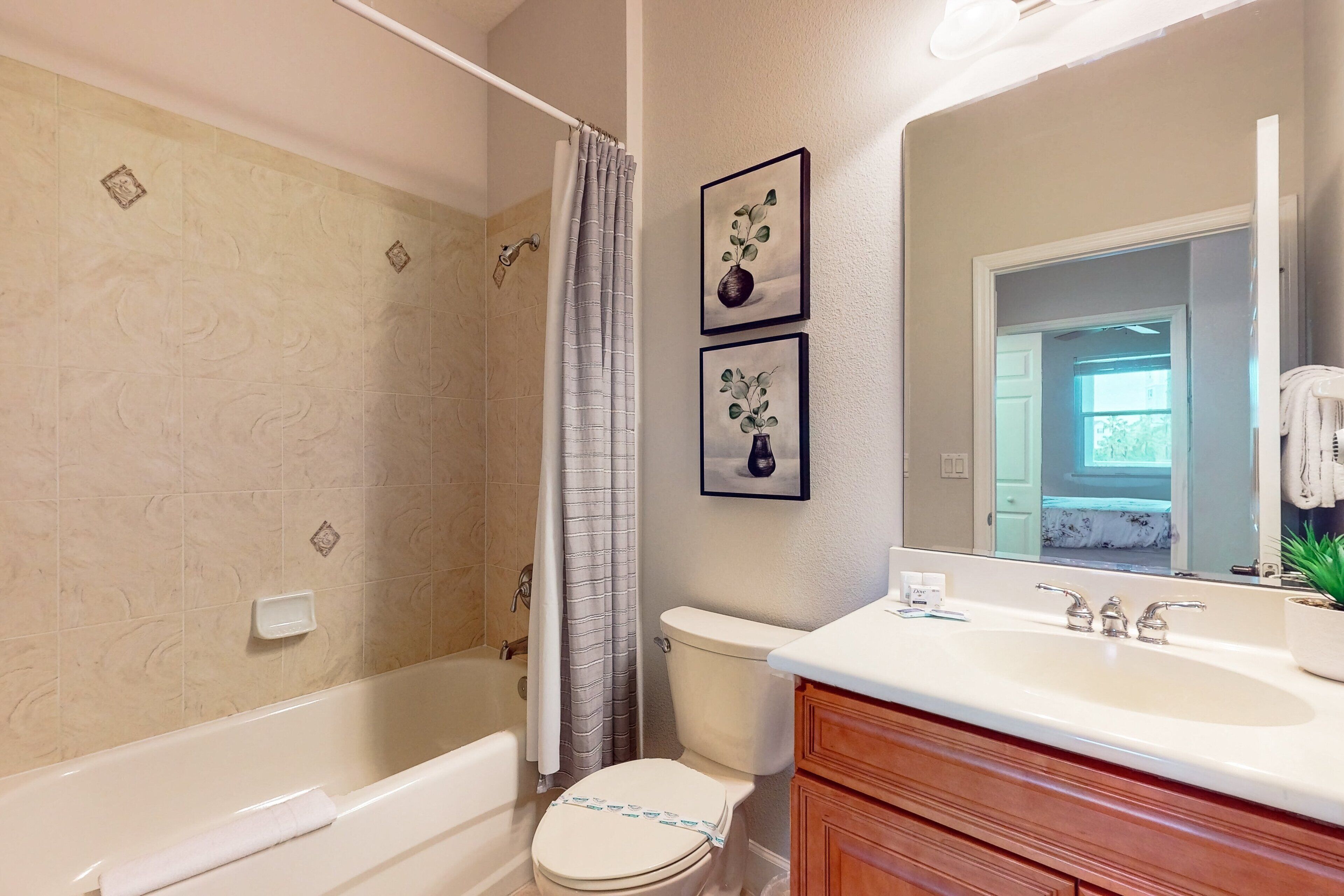 A bathroom with a bathtub, toilet, and vanity. There are two framed pictures on the wall.