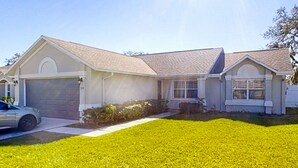 A two-story house with a garage, a front yard, and a driveway. - Pristine Palms House in Palm Coast With Enclosed Pool & Full Kitchen (Palm Coast)