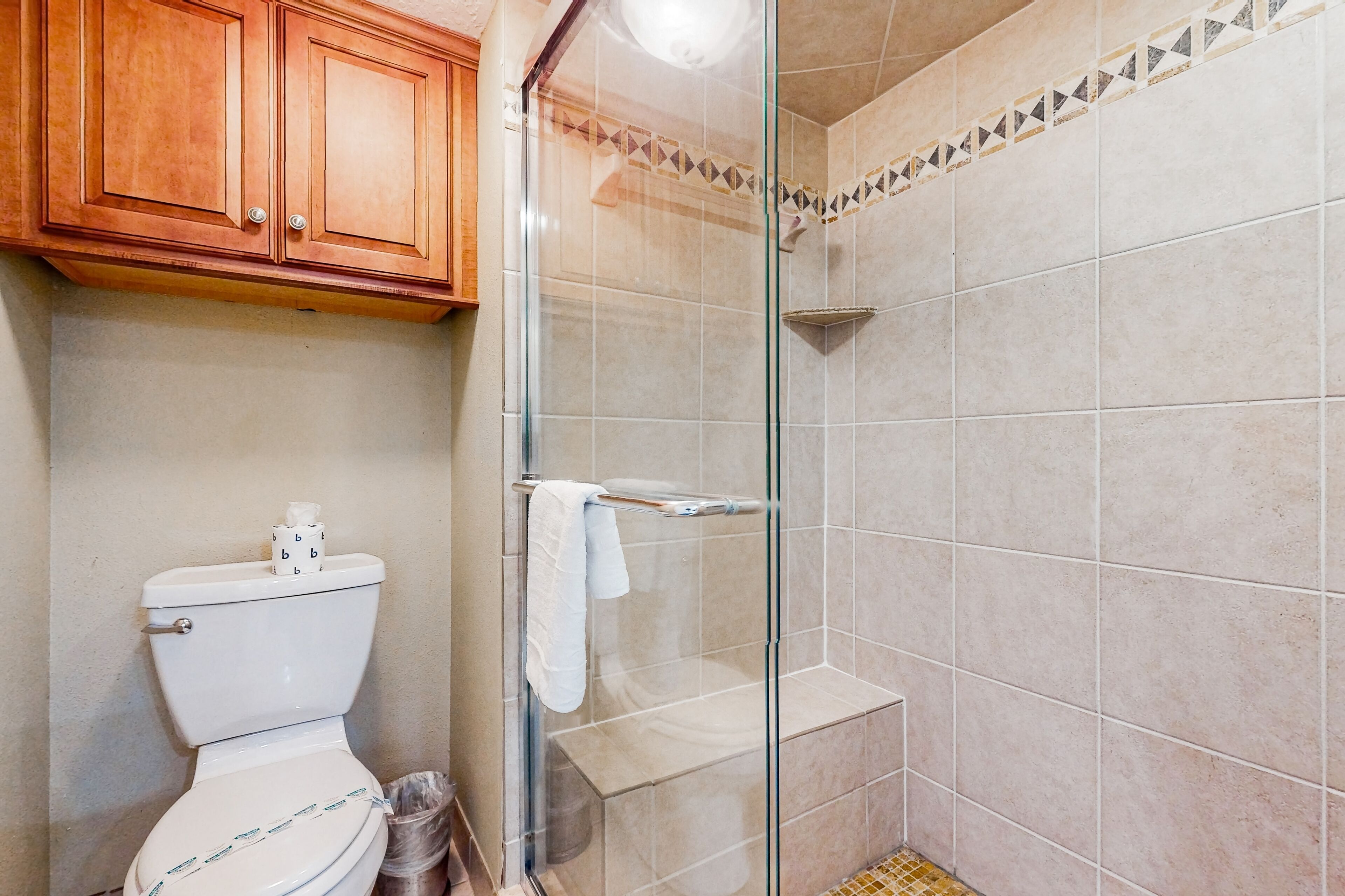A bathroom with a toilet, a glass shower enclosure, and tiled walls.