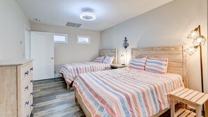 A bedroom with two beds, a wooden dresser, and a nightstand with a lamp. - Sleek Golf-front Condo With a Washer/dryer, Deck, & Central AC - dog Friendly (St. Simons Island)