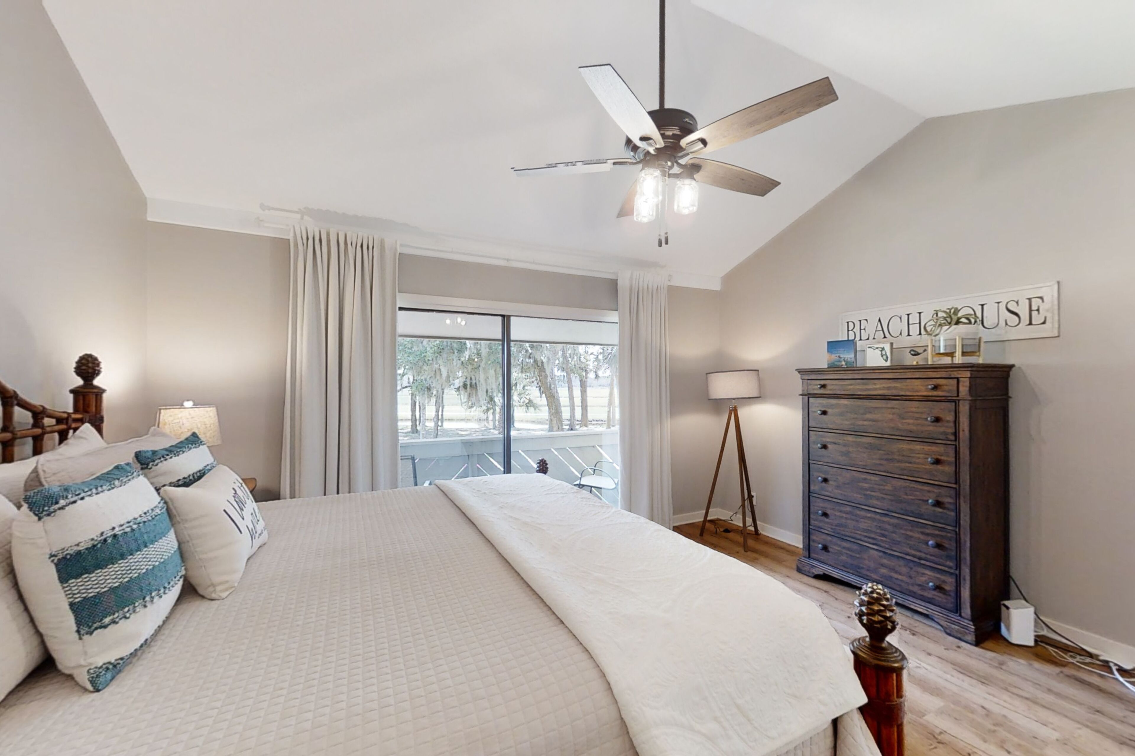 Un dormitorio con cama, ventilador de techo, cómoda y ventana con vistas.
