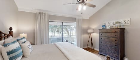 Un dormitorio con cama, ventilador de techo, cómoda y ventana con vistas.
