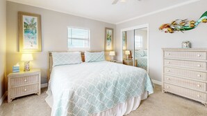 A bedroom with a bed, nightstands, a dresser, a ceiling fan, and a window. - Ocean-view Hideaway Steps to Beach Snowbird Availability (Fernandina Beach)