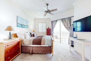 A bedroom with a bed, dresser, TV, ceiling fan, artwork, and a balcony view. - Spacious Fourth-floor Beachfront Condo With Pools, hot Tub, Fitness Room (Palm Coast)