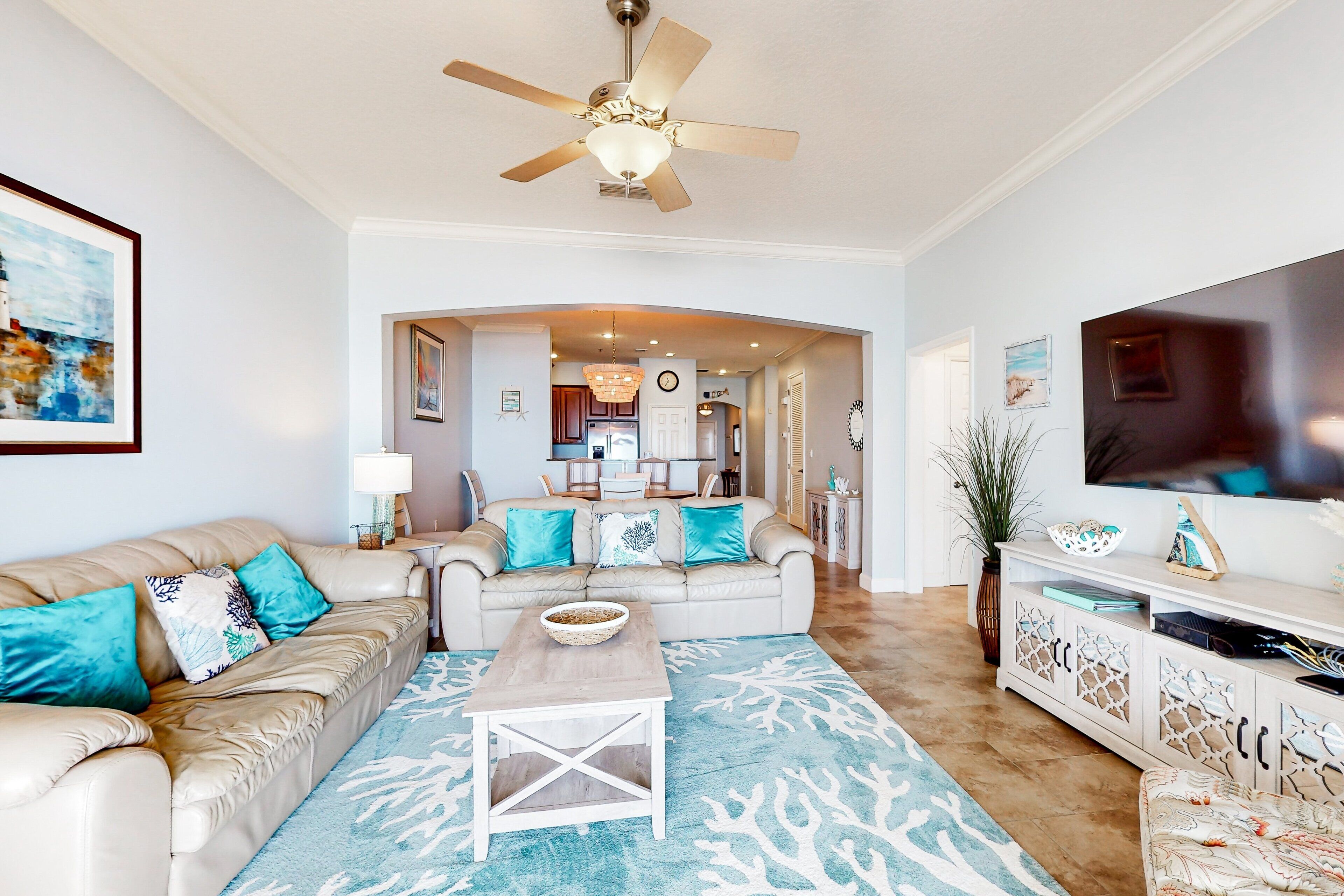 A spacious living room with a beige sofa, a coffee table, and a patterned rug.