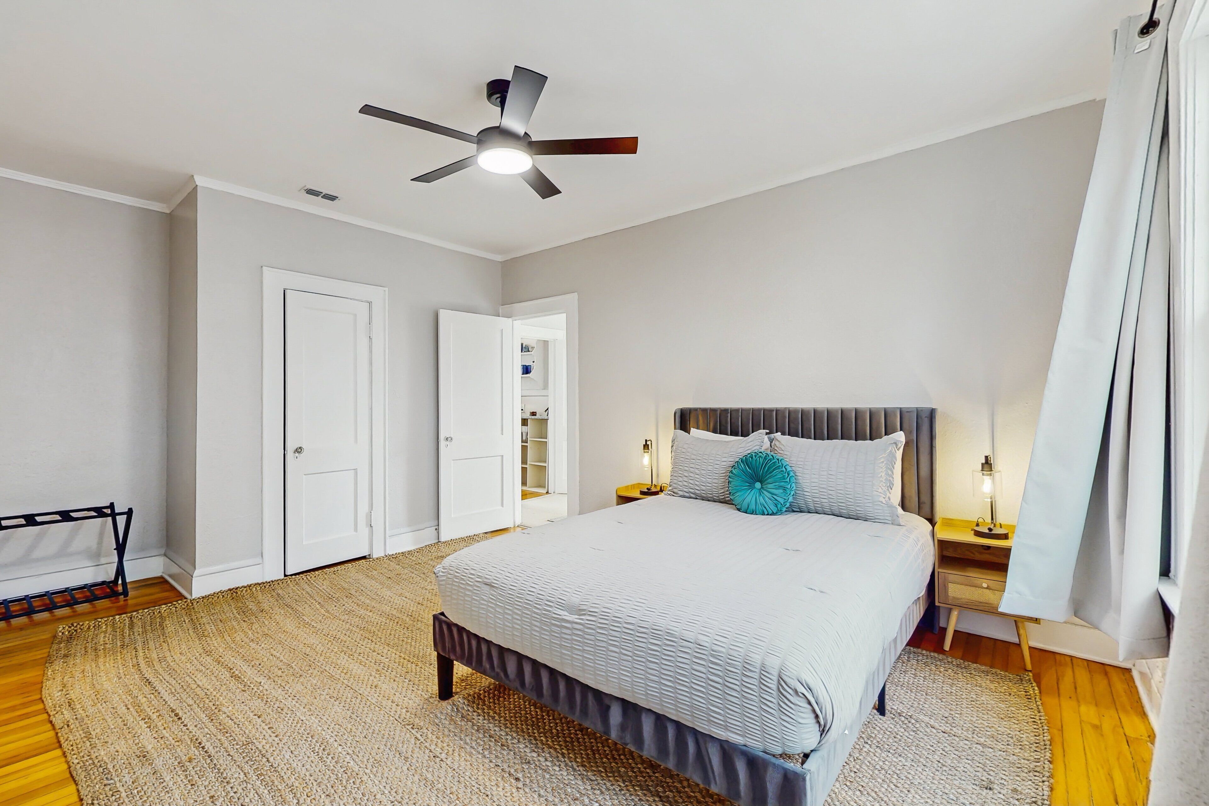 Una camera da letto con un letto, un ventilatore a soffitto, un comodino, una lampada e un armadio.