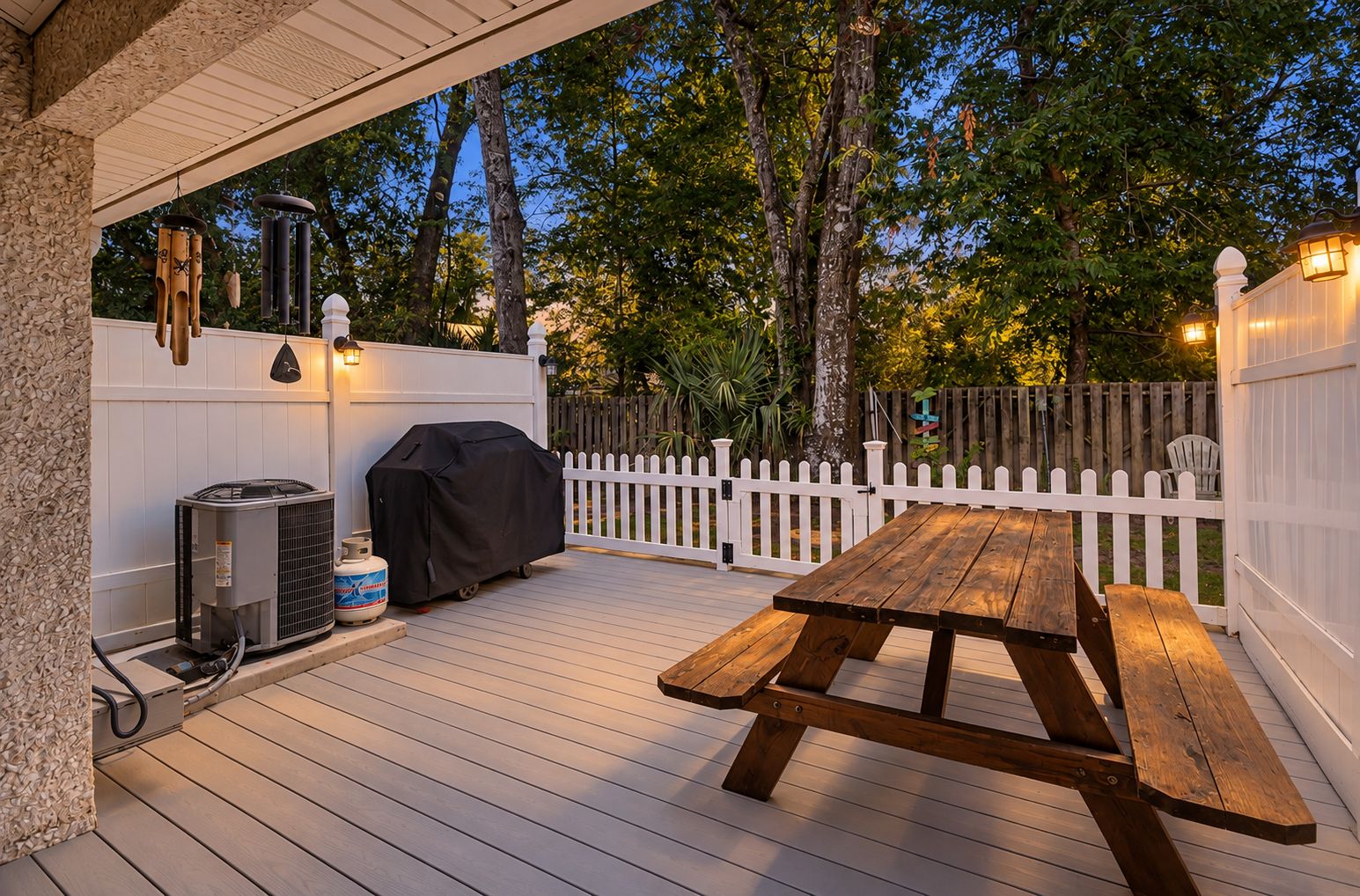 Una terraza exterior con mesa de picnic, unidad de aire acondicionado y parrilla.