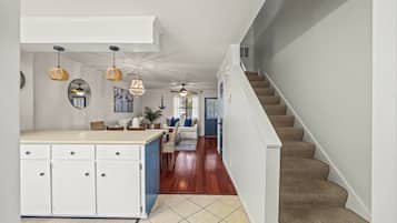 A kitchen with white cabinets, a dining area with a table and chairs, and a staircase leading to another level.