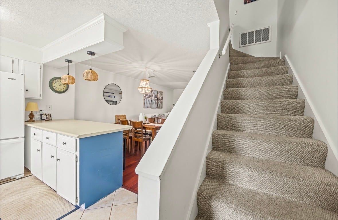 A kitchen with white cabinets, a blue island, and a dining area with chairs and a table.