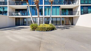 A modern hotel with multiple balconies, palm trees, and a concrete courtyard. - Renovated, Ground-floor Condo at Oceanfront Complex With Pool - Steps to Beach (St. Augustine)