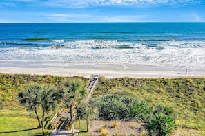 A coastal view with a beach, ocean, and a pathway leading to a boardwalk with benches. - Oceanfront Condo With Pool, Ocean Views, and Washer/dryer (St. Augustine)