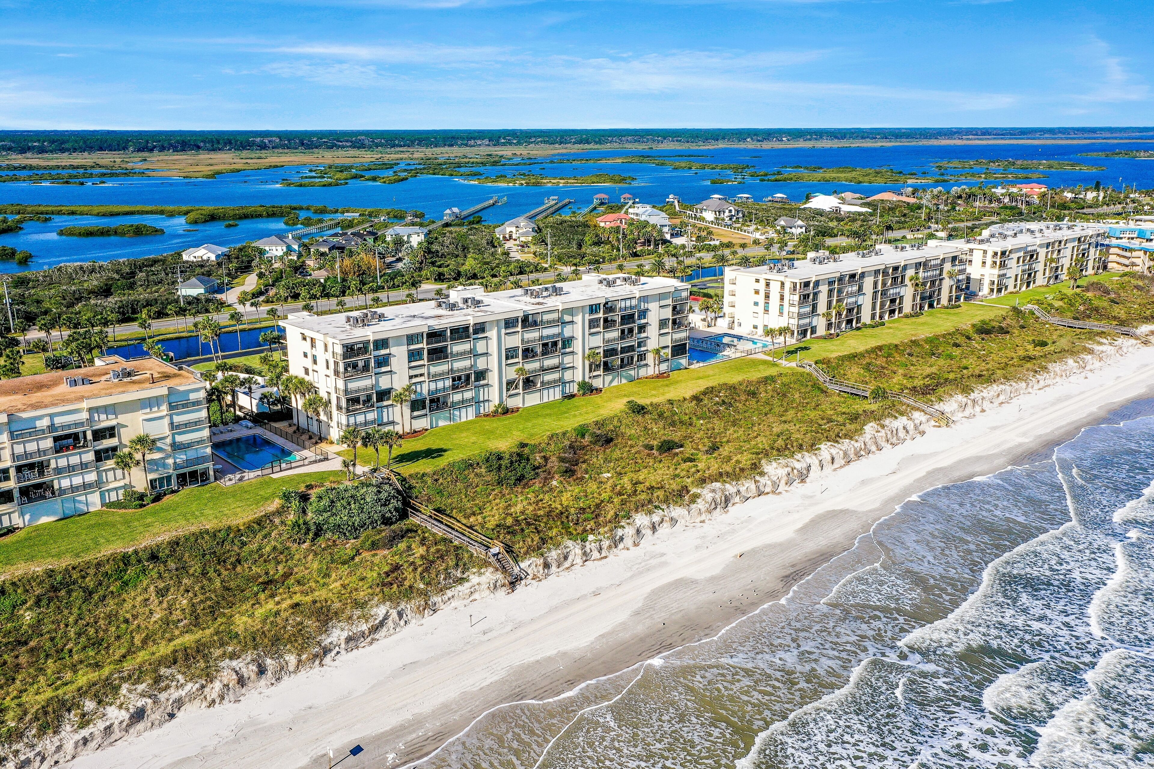 A beachfront hotel with multiple buildings, a swimming pool, and a beach.