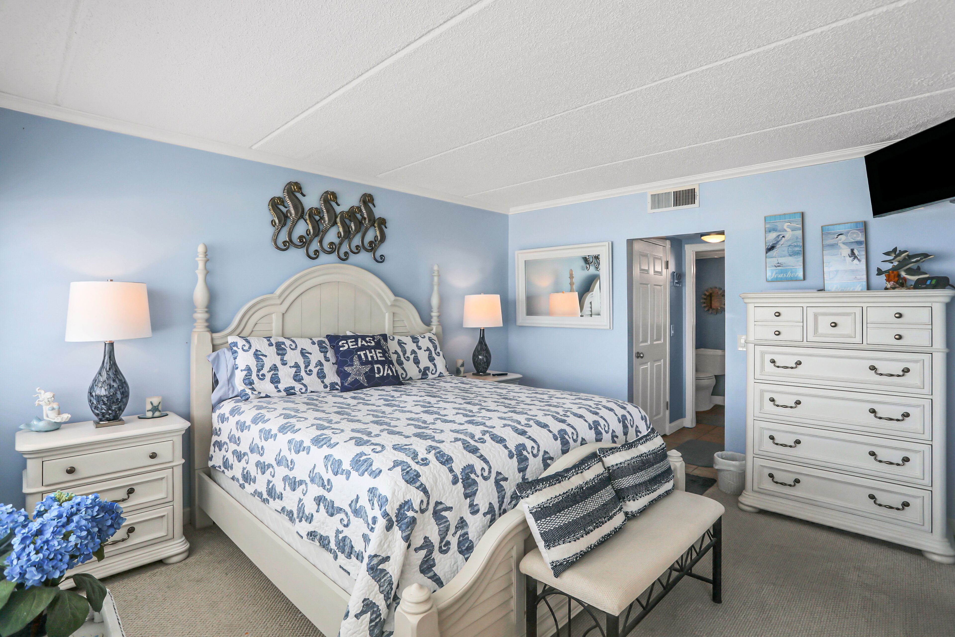 A bedroom with a bed, bedside tables, a dresser, and a bench.