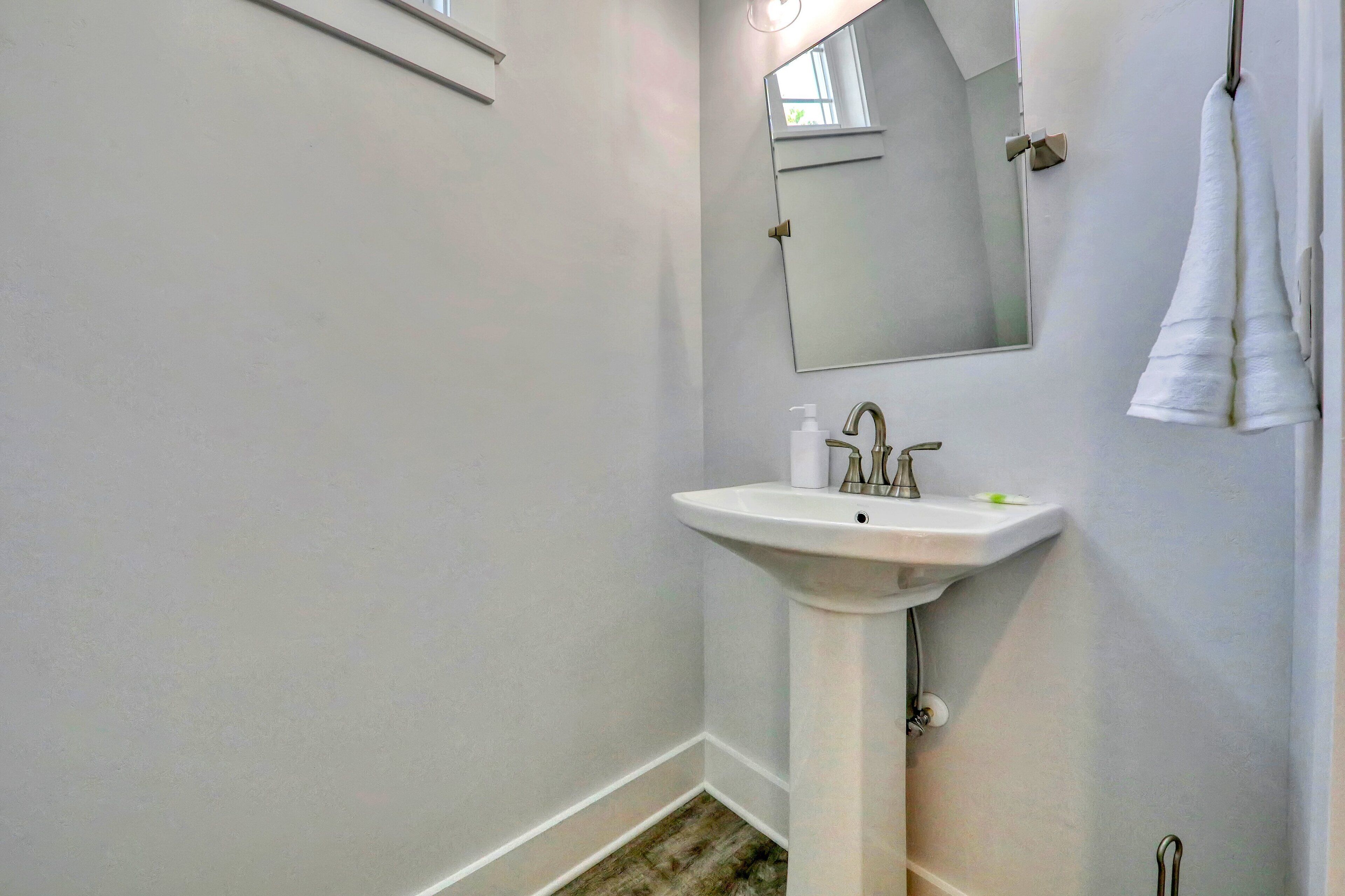 A bathroom with a white sink, a mirror, and a towel hanging on the wall.