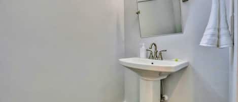 Um banheiro com pia branca, um espelho e uma toalha pendurada na parede.