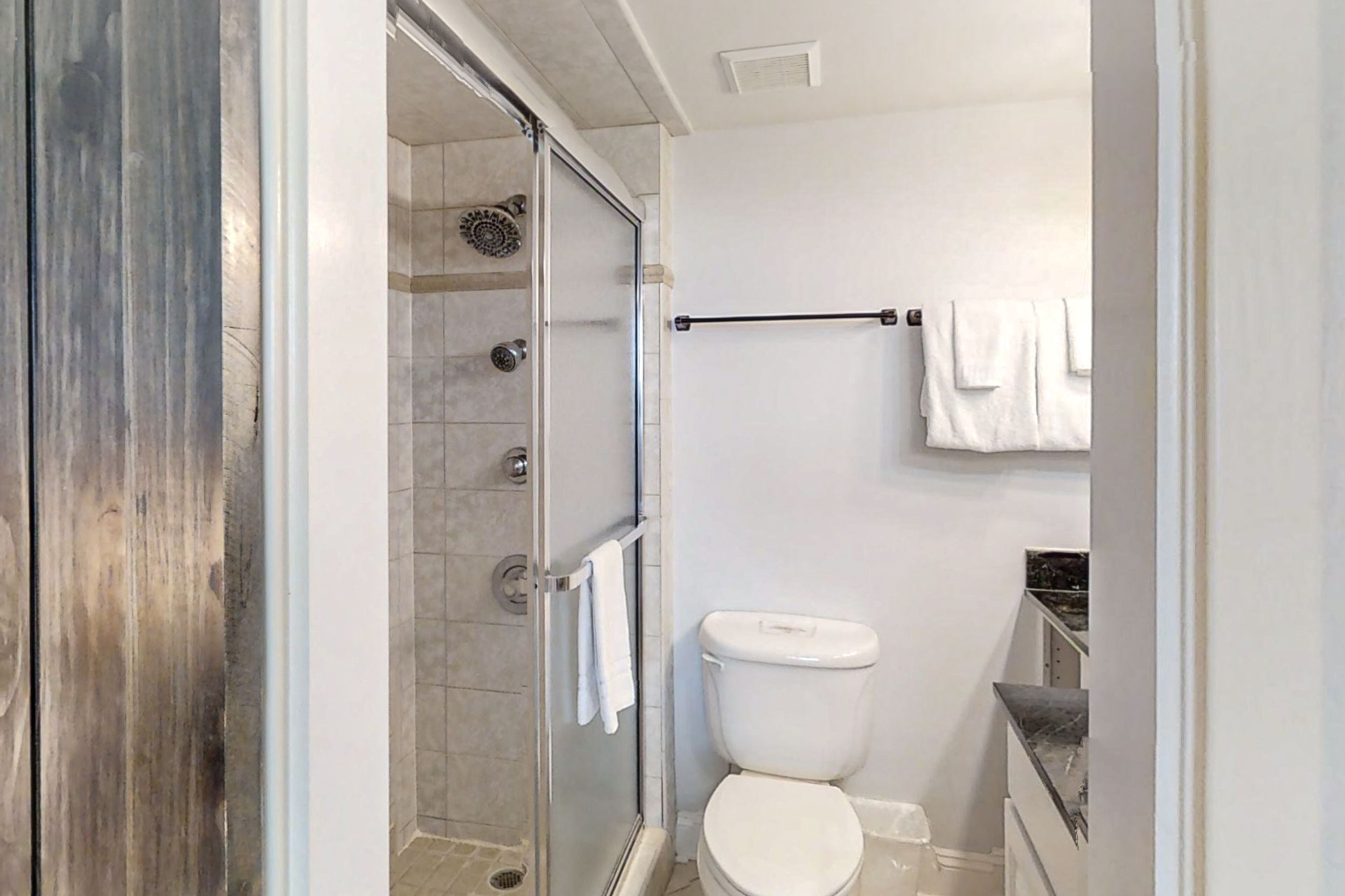 A bathroom with a glass-enclosed shower, a toilet, and a towel rack.