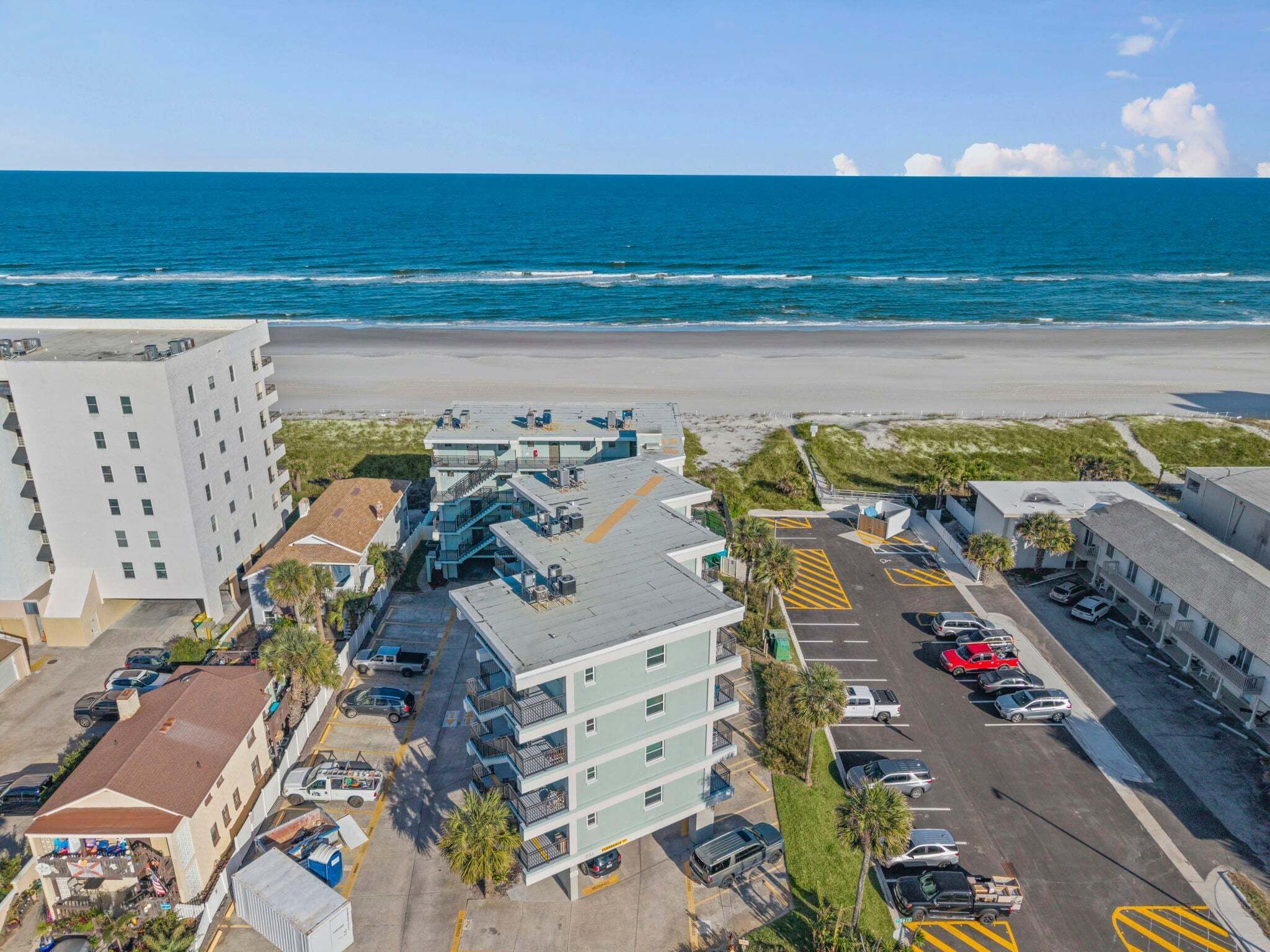 A beachfront hotel with multiple floors, parking, and a view of the ocean.