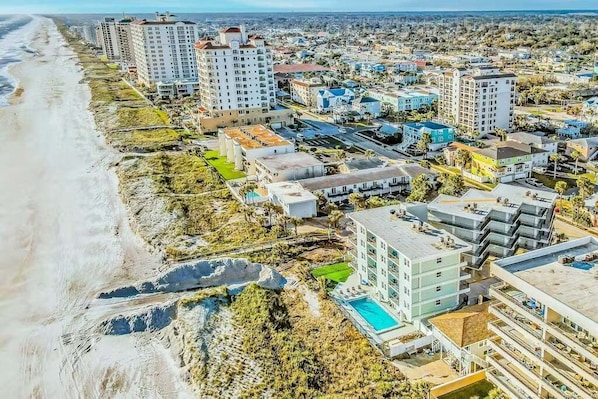 Una zona urbana costera con rascacielos, una playa y una piscina.