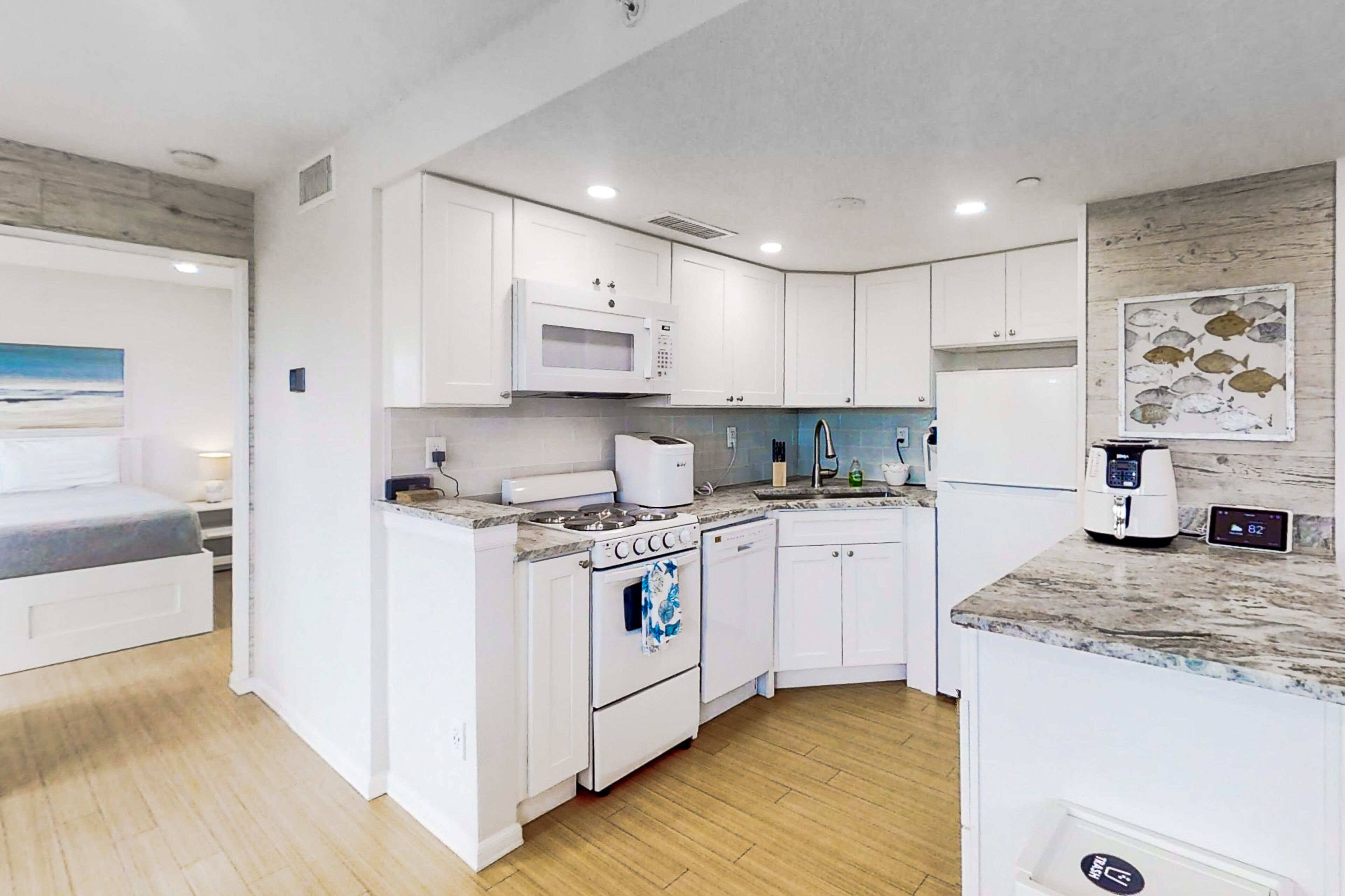 A compact kitchen with white cabinetry, a microwave, a stove, and a dishwasher.