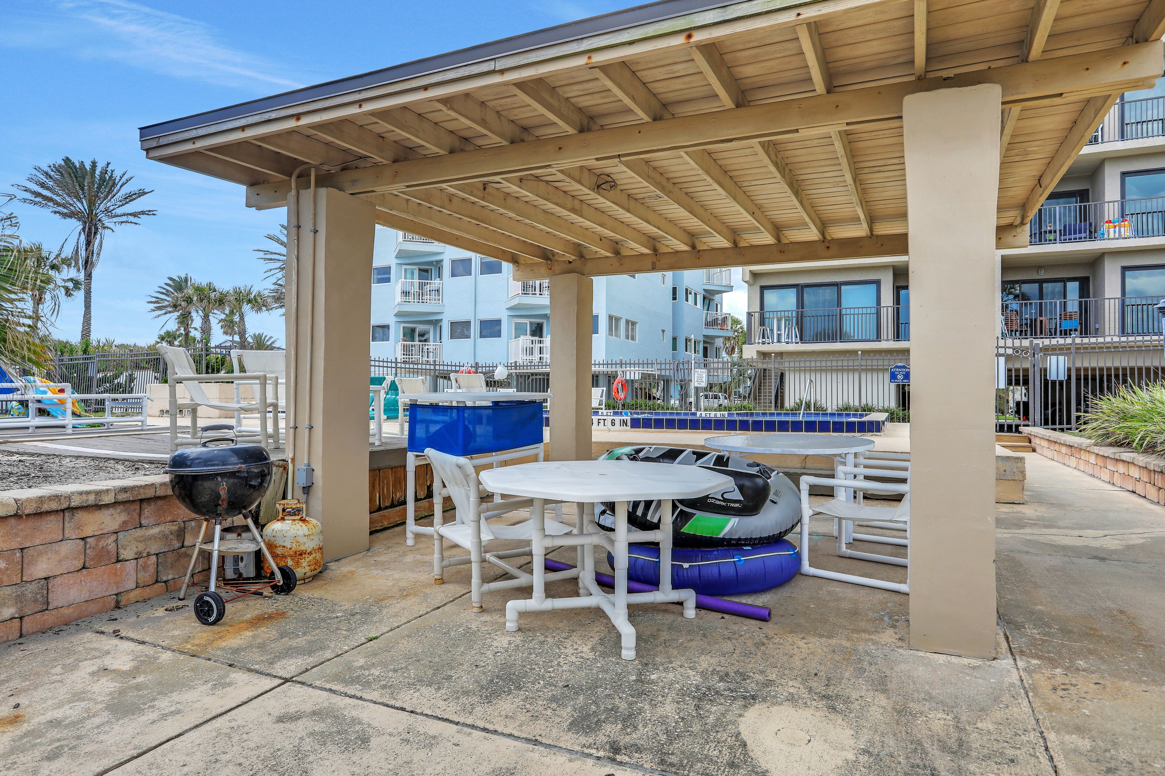 Un espace extérieur aménagé en terrasse, doté d’un coin salon couvert, d’un barbecue et de bouées gonflables.