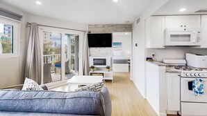 Uma cozinha moderna com eletrodomésticos brancos, uma sala de jantar com mesa e cadeiras brancas, e uma janela grande com cortinas.