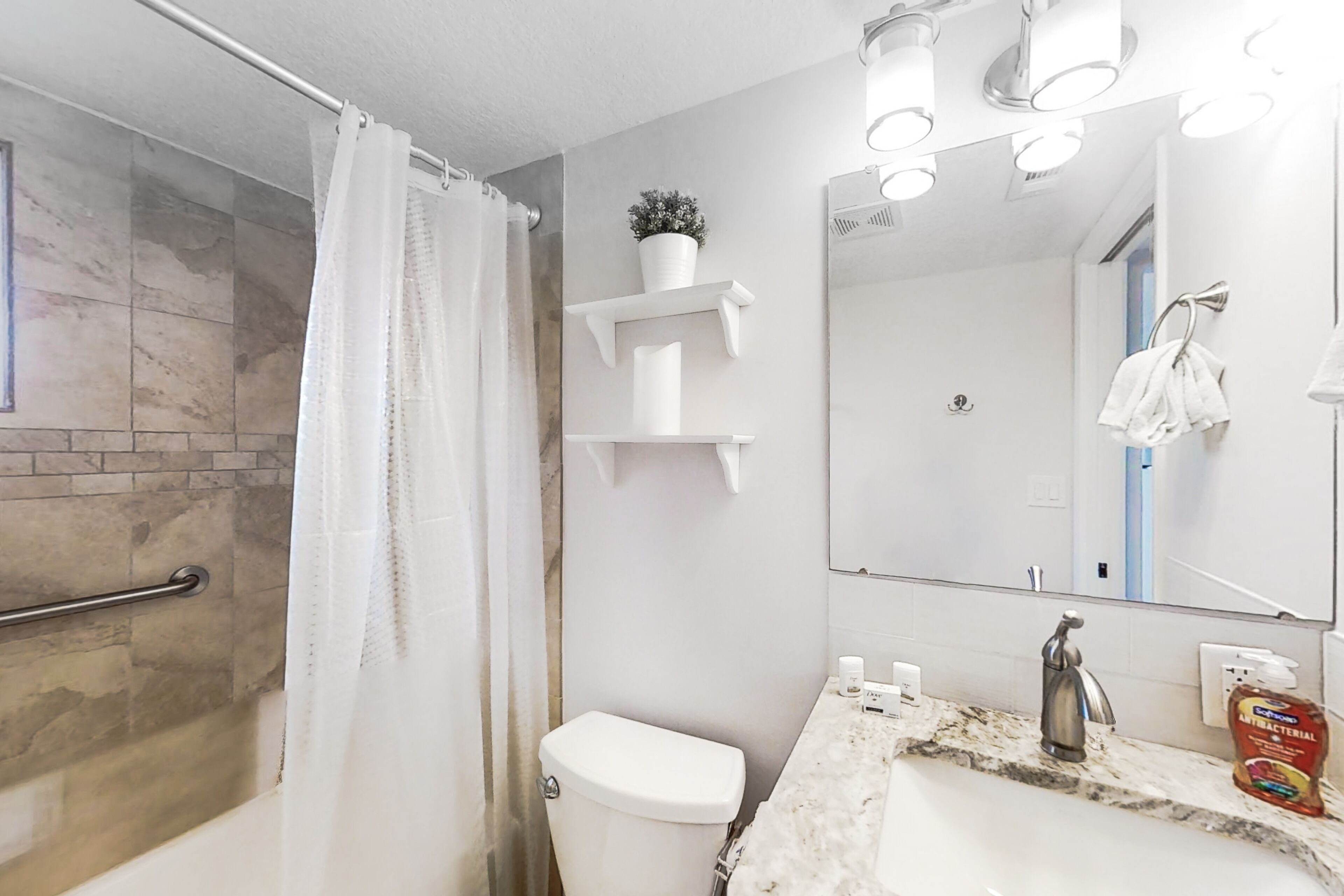 Ein Badezimmer mit Dusche, Toilette, Waschbecken und Spiegel.