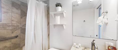 Ein Badezimmer mit Dusche, Toilette, Waschbecken und Spiegel.