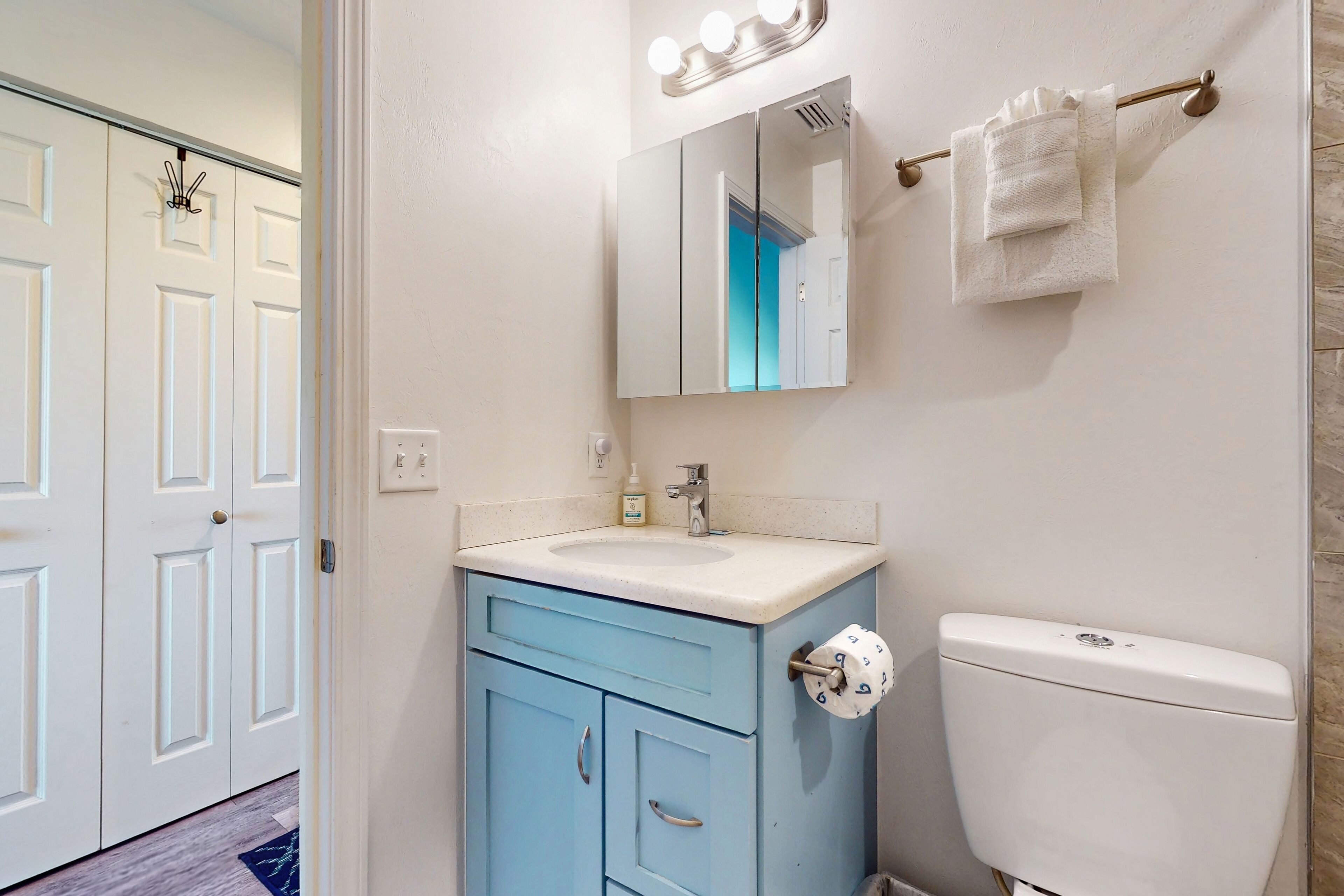 A bathroom with a white sink, blue cabinet, and a toilet.