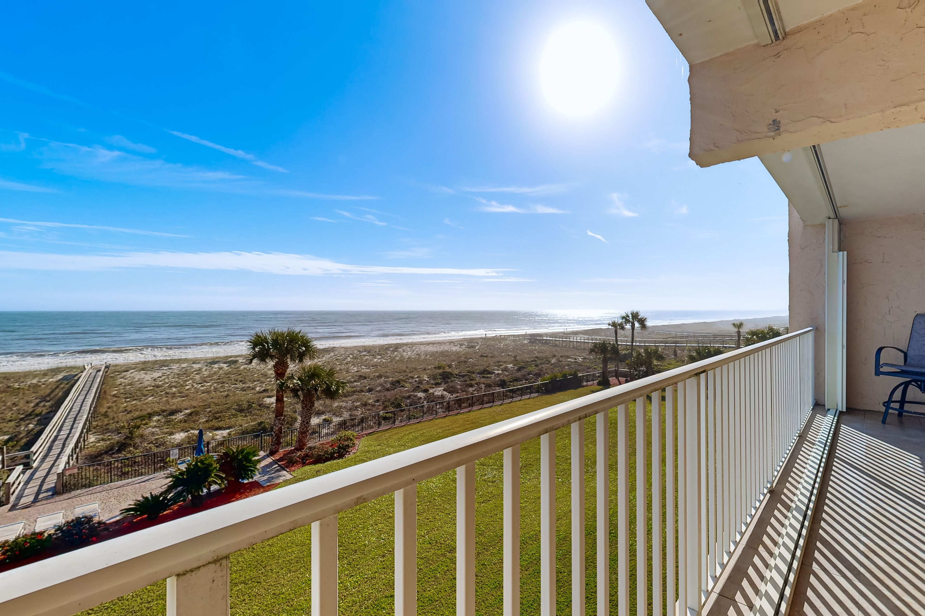 A balcony with a view of the beach and ocean.