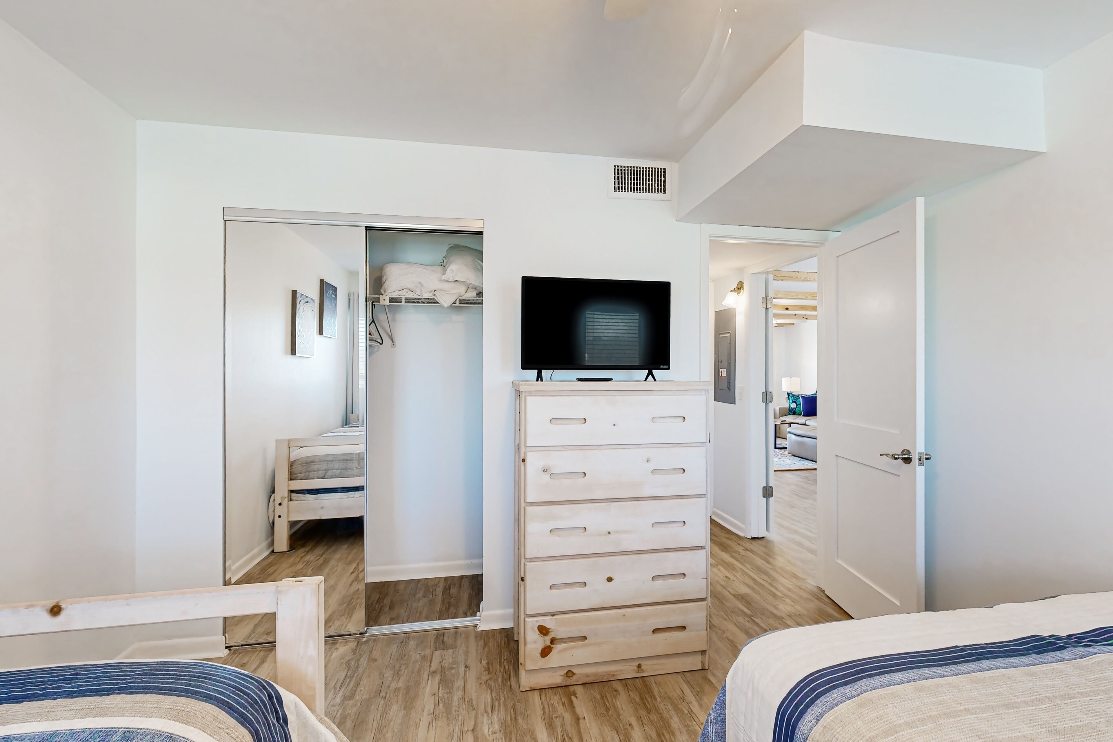 A bedroom with a bed, a dresser, a television, and a closet.