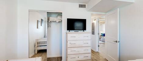 A bedroom with a bed, a dresser, a television, and a closet.