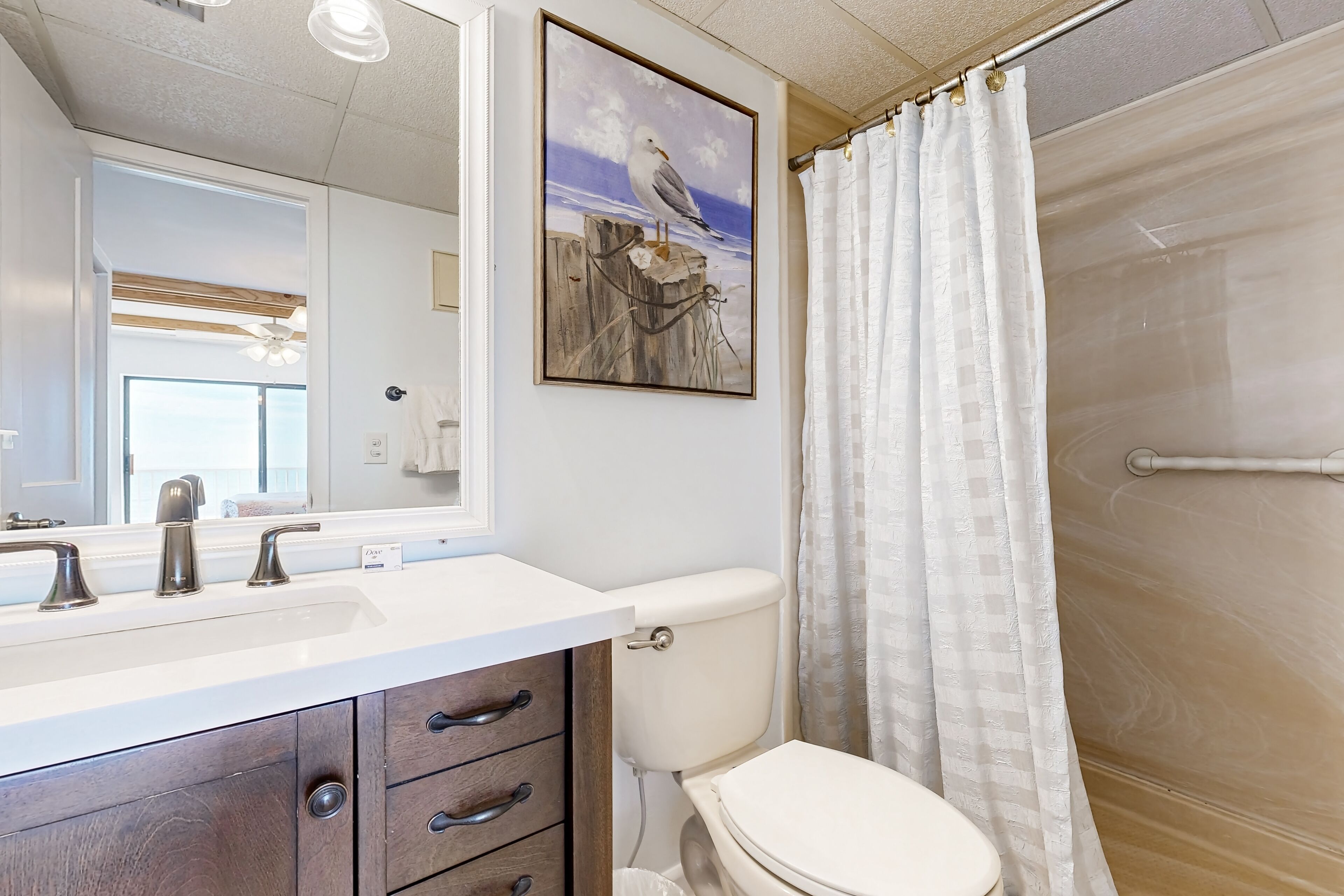 A bathroom with a white sink, two faucets, a toilet, and a shower curtain.