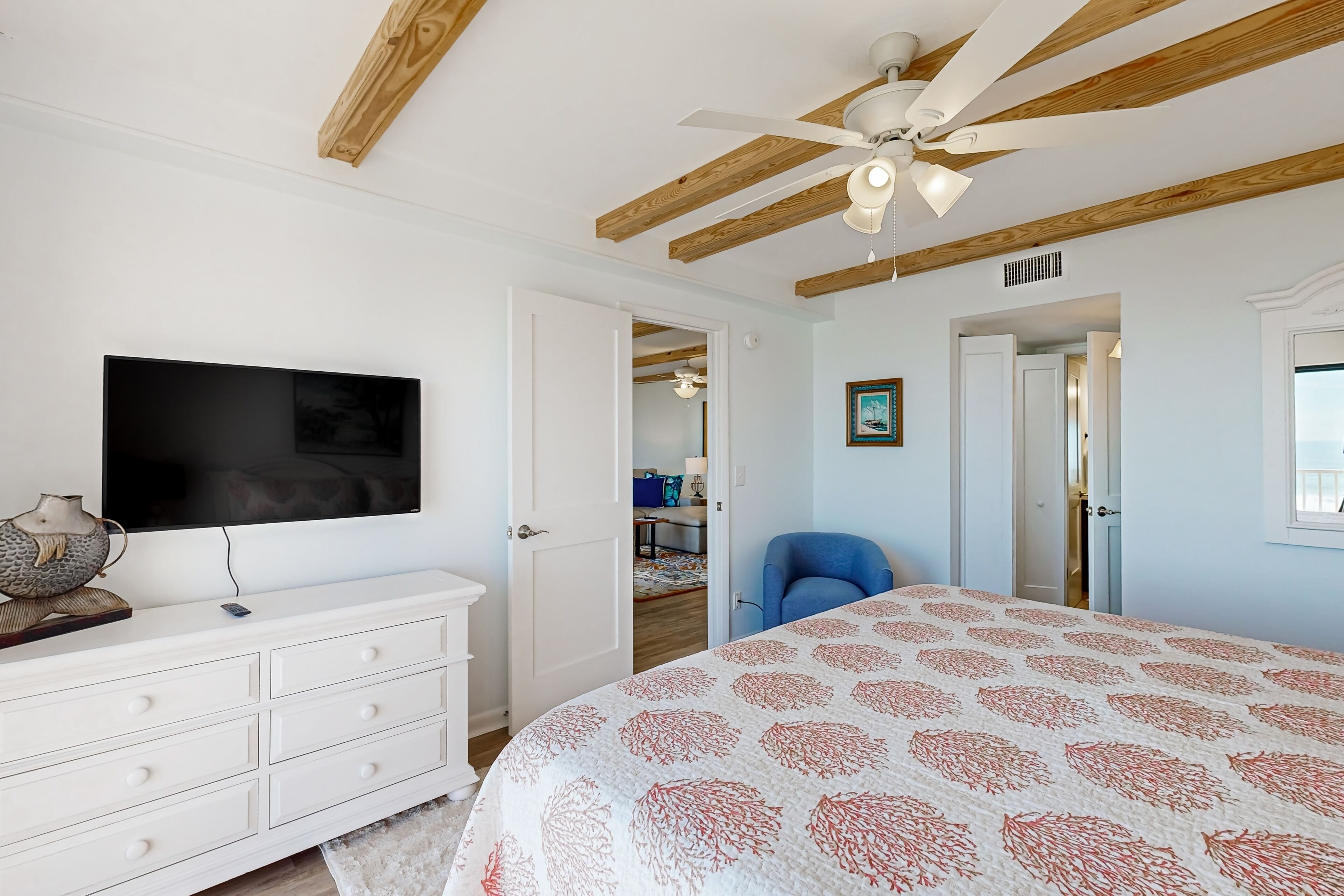 Een slaapkamer met een bed, een plafondventilator, een televisie en een dressoir.